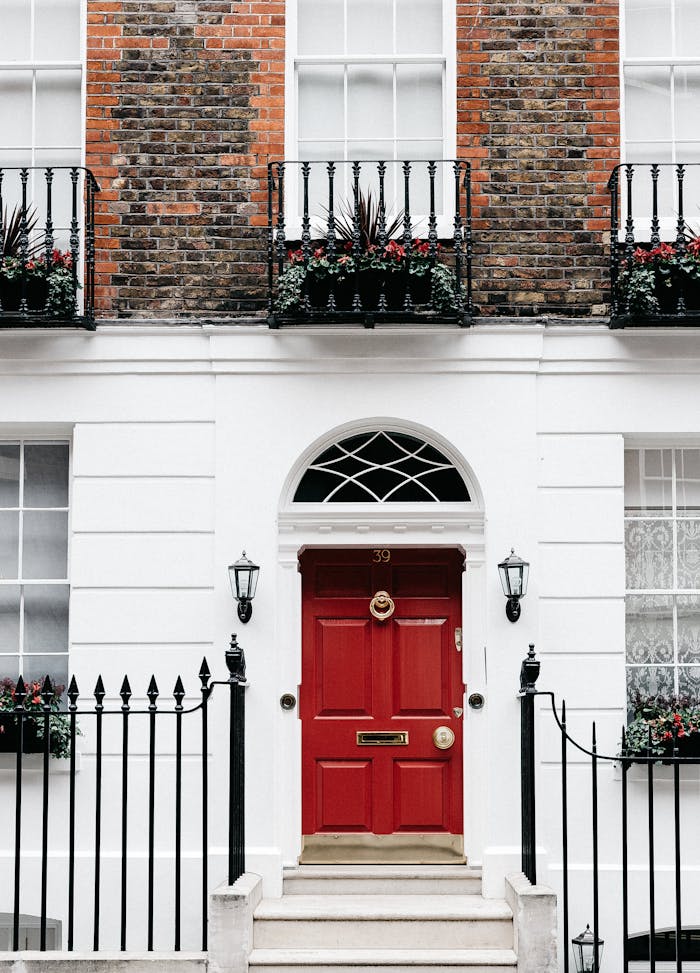 Exterior of aged residential house with red door decorated with lanterns and potted plants